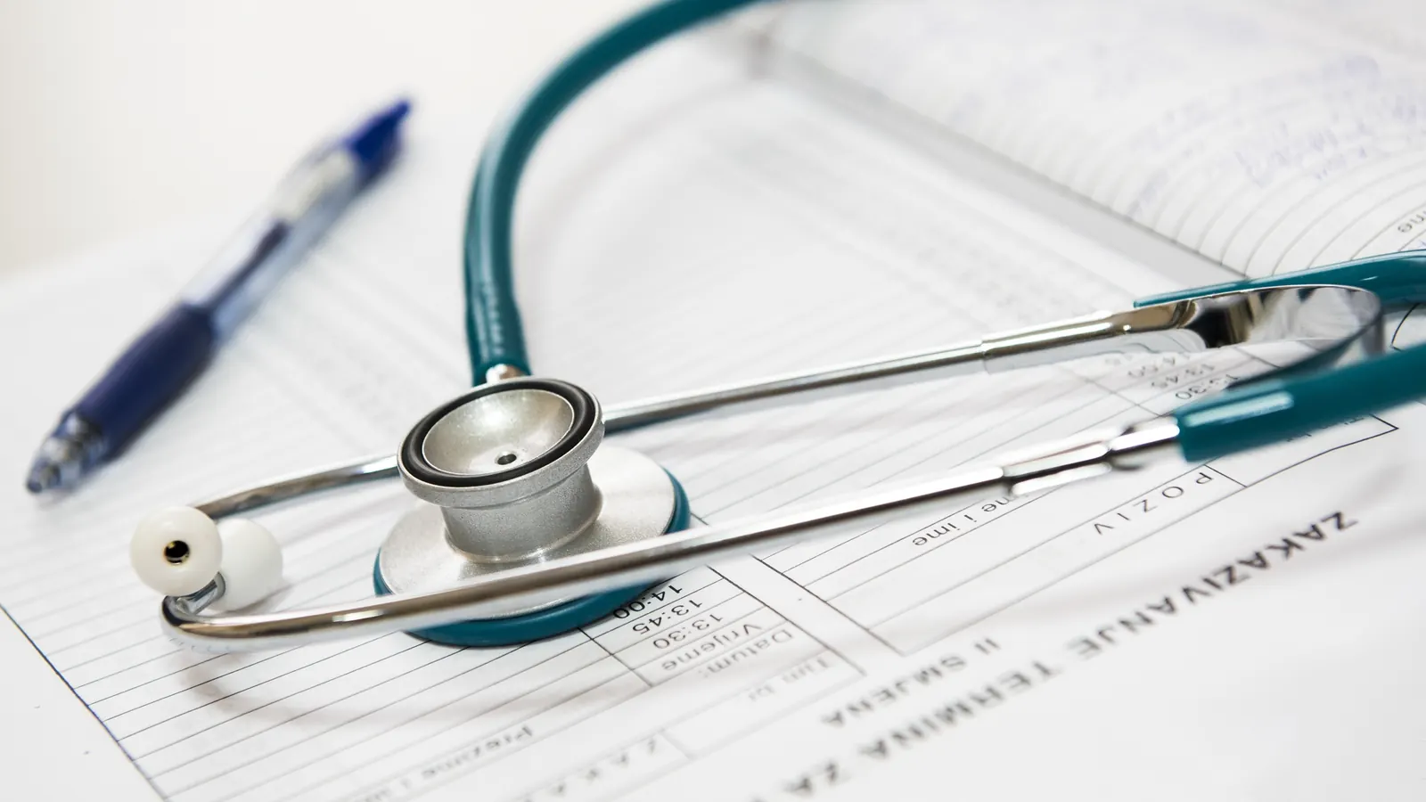 A stethoscope resting on a medical form with a pen