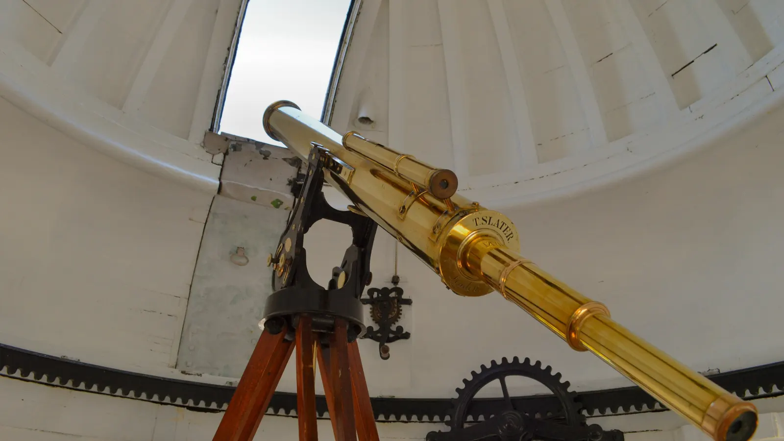 A brass refracting telescope inside an observatory dome