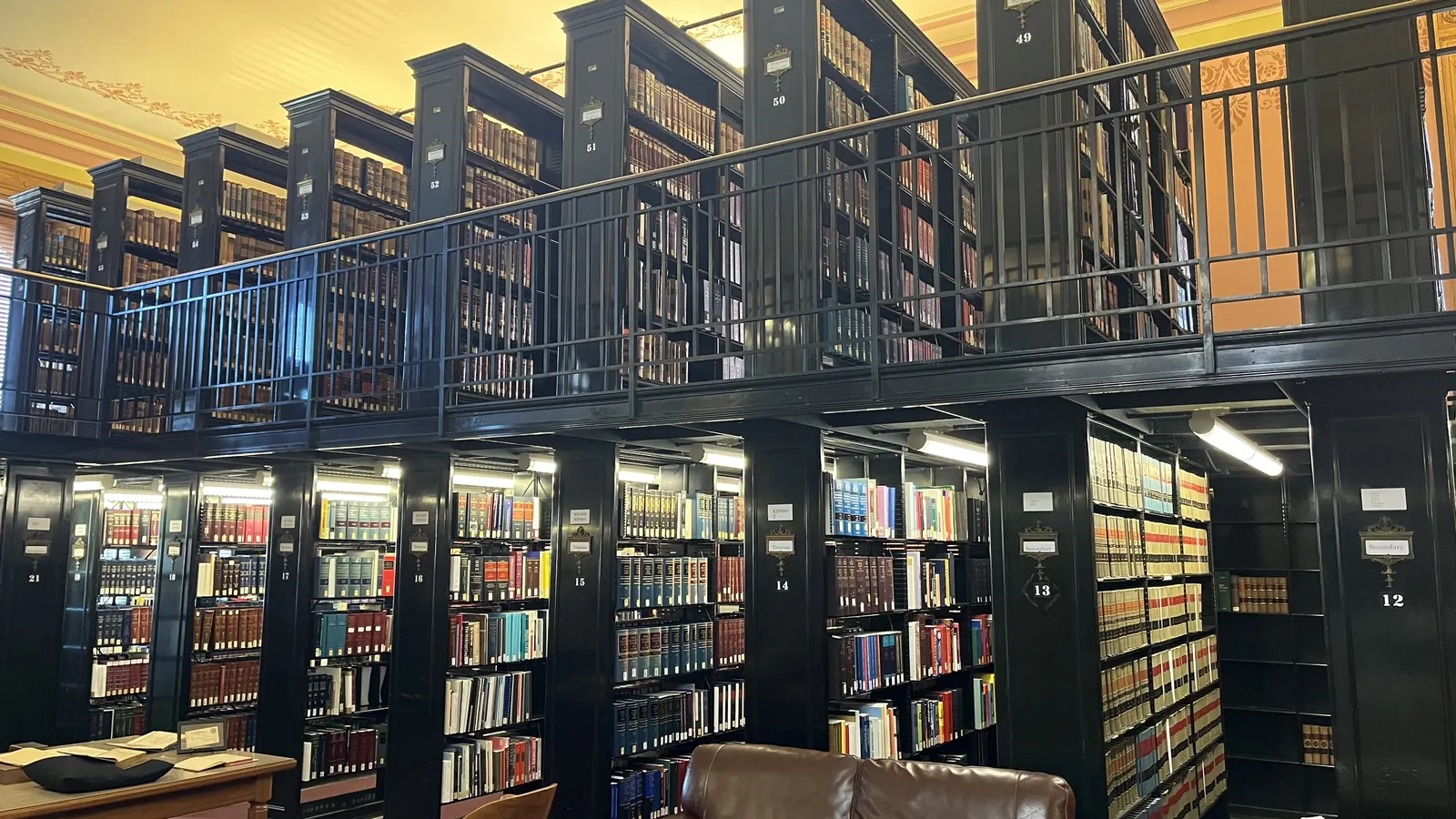 Tall dark bookcases on two levels in a library reading room
