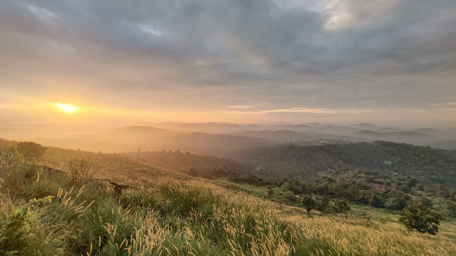 Sunrise over rolling hills with mist in the valleys