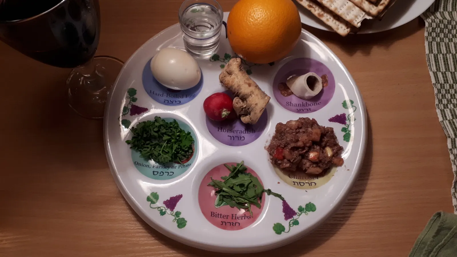 A Passover seder plate with matzah and a cup of wine on the table